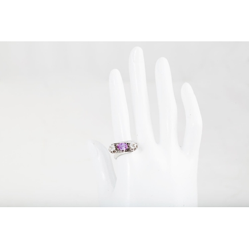 384 - A PINK SAPPHIRE AND DIAMOND THREE STONE RING, of cross over design, set with an oval sapphire and ol... 