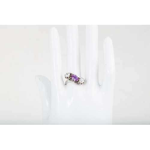 384 - A PINK SAPPHIRE AND DIAMOND THREE STONE RING, of cross over design, set with an oval sapphire and ol... 