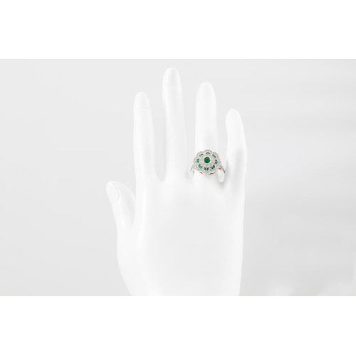 6 - A DIAMOND AND EMERALD CLUSTER RING, of floral form, the central emerald collet set to a three rowed ... 