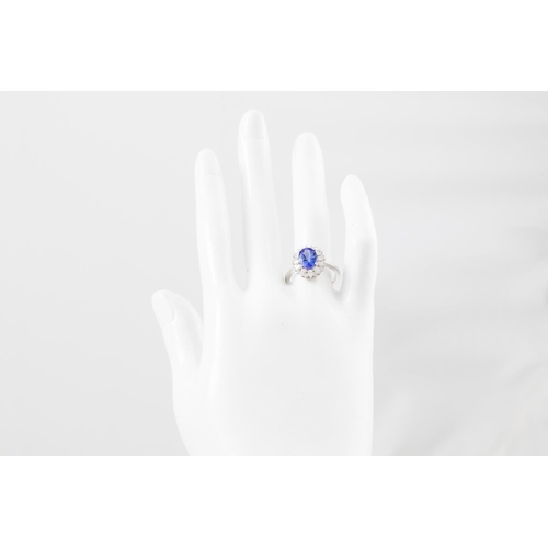 83 - A DIAMOND AND TANZANITE CLUSTER RING, the oval tanzanite to a pear and brilliant cut diamond surroun... 