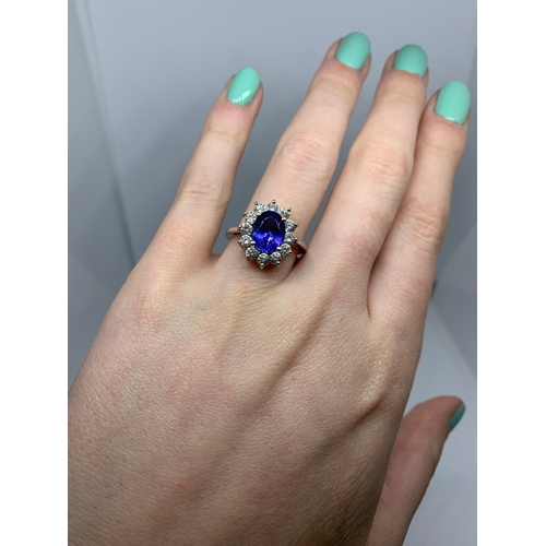 11 - A TANZANITE AND DIAMOND CLUSTER RING, the oval tanzanite to a brilliant cut diamond surround, mounte... 