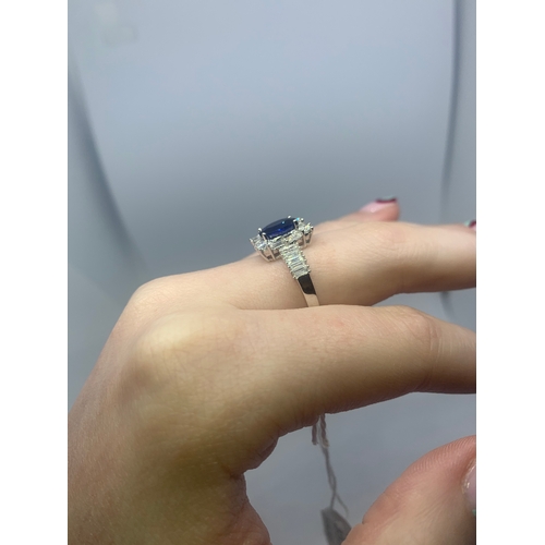 357 - A SAPPHIRE AND DIAMOND CLUSTER RING, the oval sapphire to a brilliant and baguette cut diamond surro... 