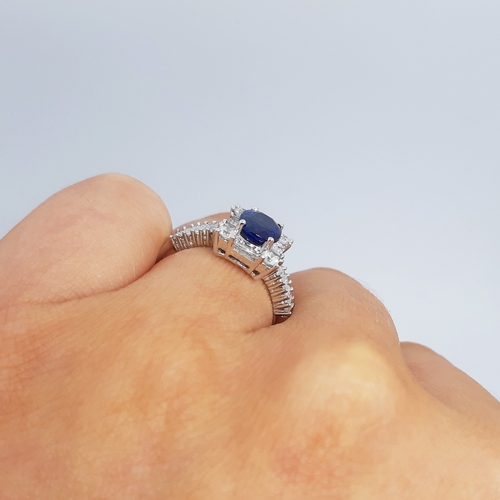 357 - A SAPPHIRE AND DIAMOND CLUSTER RING, the oval sapphire to a brilliant and baguette cut diamond surro... 