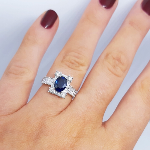 357 - A SAPPHIRE AND DIAMOND CLUSTER RING, the oval sapphire to a brilliant and baguette cut diamond surro... 