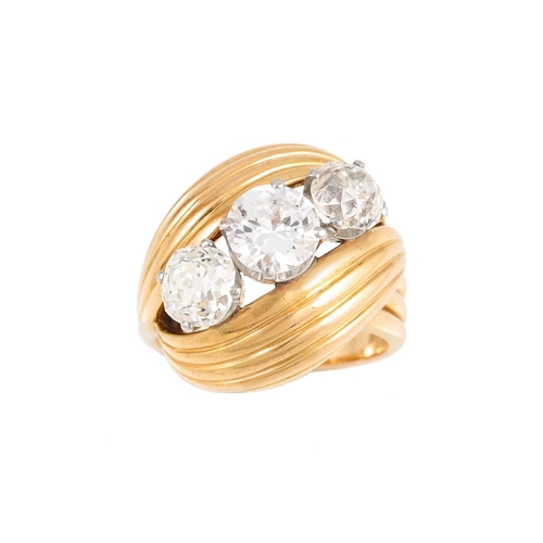 453 - A THREE STONE DIAMOND RING, of retro design, the old cut diamonds to a cross over fluted yellow gold... 