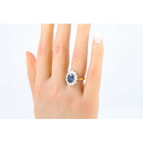 245 - A DIAMOND AND SAPPHIRE CLUSTER RING, the oval sapphire to a brilliant cut diamond surround, mounted ... 