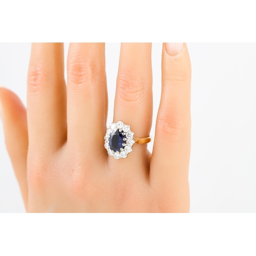 245 - A DIAMOND AND SAPPHIRE CLUSTER RING, the oval sapphire to a brilliant cut diamond surround, mounted ... 