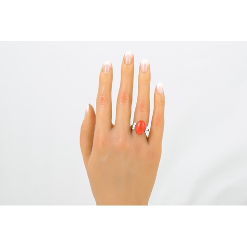 334 - A CORAL AND DIAMOND RING, the cabochon coral to diamond set shoulders, mounted in 18ct white gold. E... 