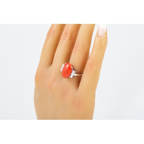 334 - A CORAL AND DIAMOND RING, the cabochon coral to diamond set shoulders, mounted in 18ct white gold. E... 