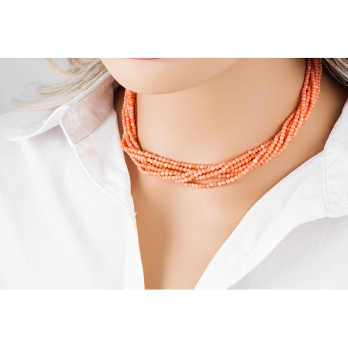 367 - A CORAL BEADED NECKLACE, comprising seven twisted strands, to an 18ct gold bow clasp