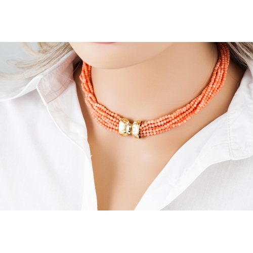 367 - A CORAL BEADED NECKLACE, comprising seven twisted strands, to an 18ct gold bow clasp