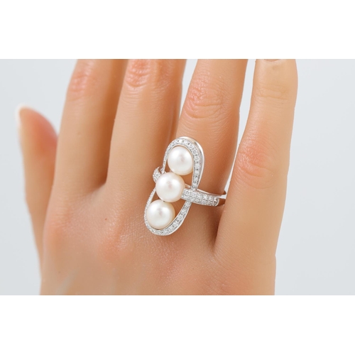 403 - A DIAMOND AND PEARL FINGER LINE RING, the three pearls set within a diamond surround, mounted in 18c... 