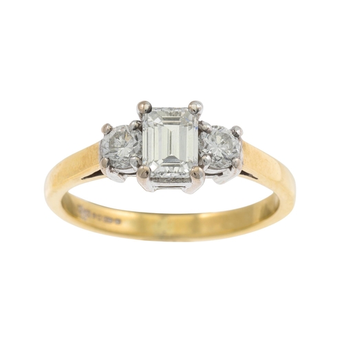 11 - A THREE STONE DIAMOND RING, the emerald cut diamond flanked by brilliant cut diamonds, mounted in 18... 