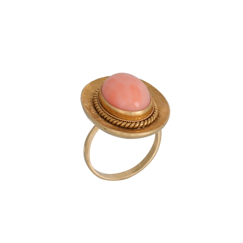 322 - A VINTAGE CORAL RING, the cabochon stone to a textured 18ct gold surround, size O