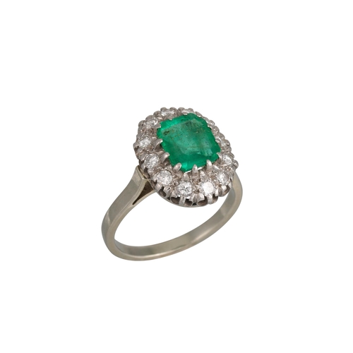 414 - A VINTAGE EMERALD AND DIAMOND CLUSTER RING, the rectangular emerald to a brilliant cut diamond surro... 