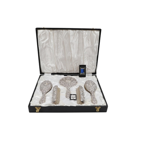 426 - A MODERN CASED SILVER EMBOSSED DRESSING TABLE SET, compact mirror, two hairbrushes and two cloths br... 