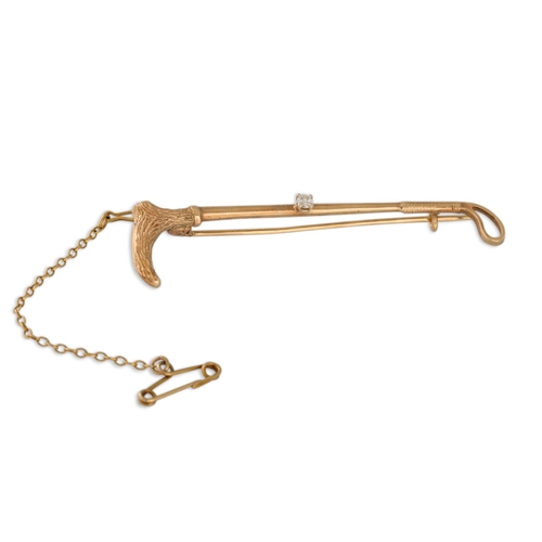 62 - A DIAMOND SET RIDING CROP BROOCH, mounted in 9ct yellow gold.