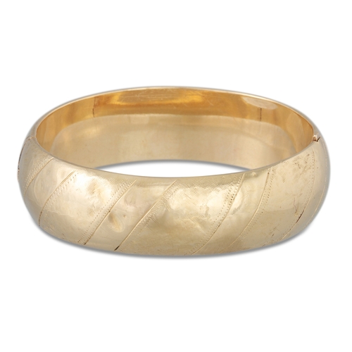 1 - A VINTAGE GOLD HINGED HOLLOW BANGLE, with engraved decoration, 24 g.