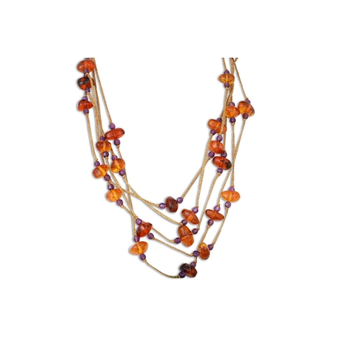 152 - AN AMBER NECKLACE, on a cord with gold fittings