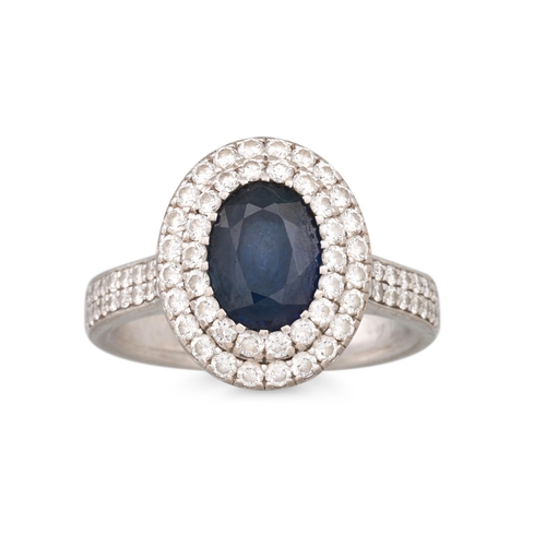 165 - A SAPPHIRE AND DIAMOND CLUSTER RING, the oval sapphire to a two rowed diamond halo surround, to diam... 