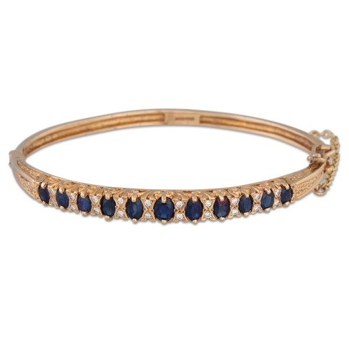 198 - A SAPPHIRE AND DIAMOND SET HINGED BANGLE, mounted in 9ct gold