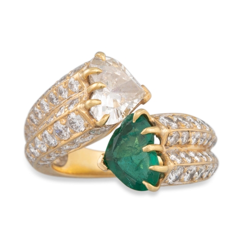 206 - A DIAMOND AND EMERALD RING, of cross over design, the pavé set mount terminating in a heart shaped d... 