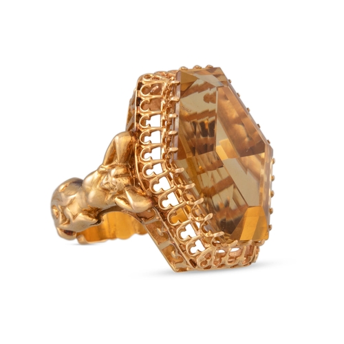 207 - A CITRINE RING, the large hexagonal shaped ring to a carved yellow gold mount depicting female forms... 