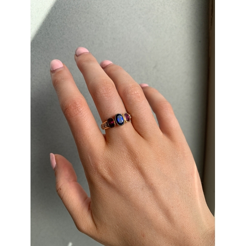 143 - A SAPPHIRE AND RUBY THREE STONE RING, the oval sapphire and rubies to diamond shoulders, mounted in ... 