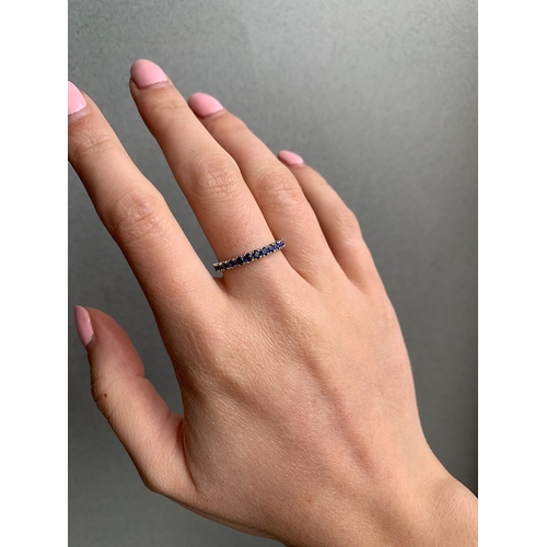 253 - A SAPPHIRE HALF ETERNITY RING, mounted in 18ct white gold. Estimated weight of sapphires: 0.70 ct, s... 