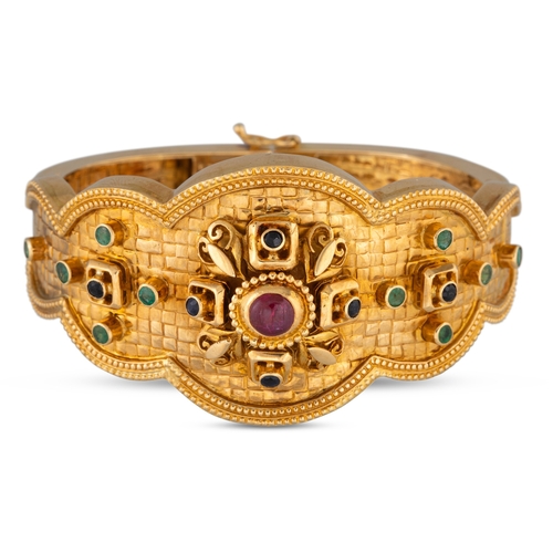 148 - A LALOUNIS MULTI GEM SET BANGLE, Eastern style, set with ruby, emerald and sapphire in 18ct yellow g... 