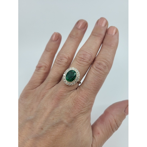 39 - AN EMERALD AND DIAMOND SET CLUSTER RING, the central oval emerald to diamond set surround, mounted i... 