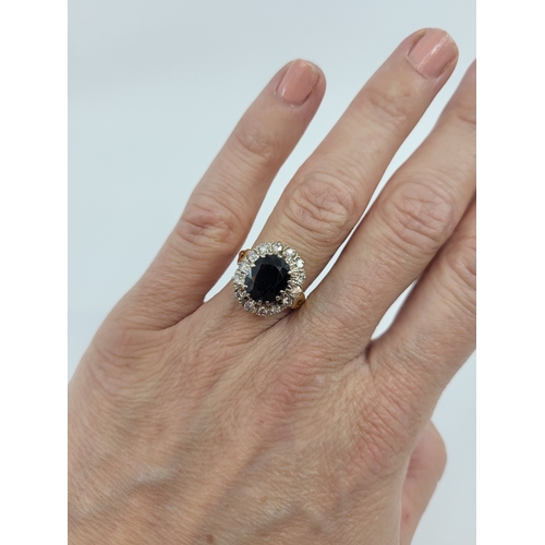 44 - A SAPPHIRE AND DIAMOND CLUSTER RING, the central oval sapphire to diamond set surround, stamped 18ct... 