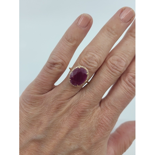 103 - A RUBY AND DIAMOND SET CLUSTER RING, the central oval ruby to diamond set surround, mounted in 14ct ... 