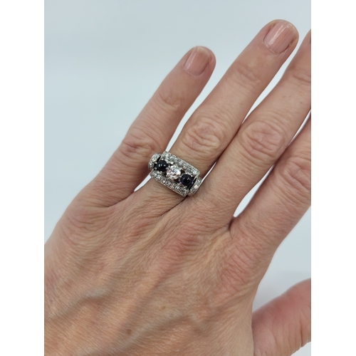 104 - A RETRO DIAMOND AND SAPPHIRE SET CLUSTER RING, the central trio of diamonds flanked by two cabochon ... 