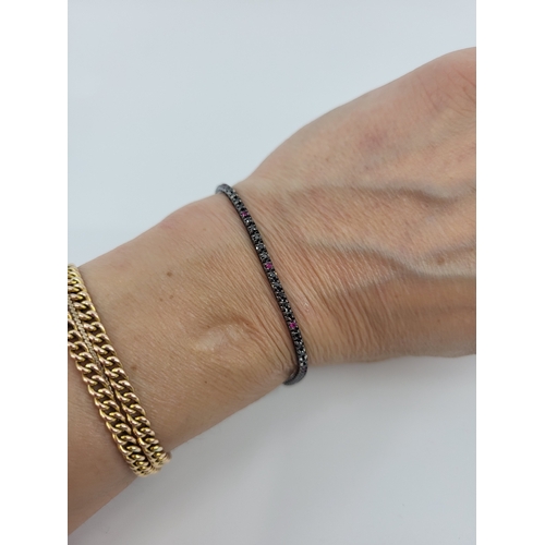112 - A BLACK DIAMOND AND RUBY LINE BRACELET, mounted in black rhodium-plated 18ct gold. Estimated: weight... 