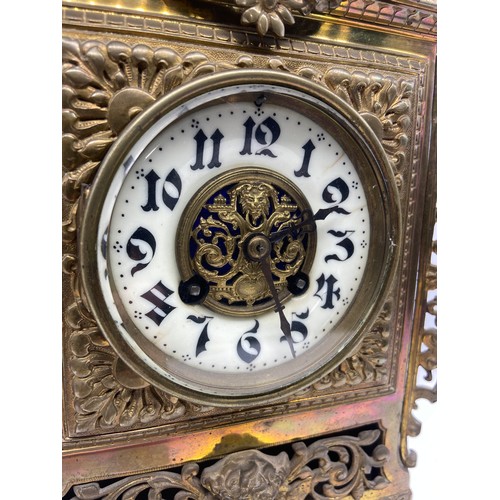 599 - A PIERCED BRASS MANTLE CLOCK WITH A CHERUB FIGURE TO BASE AND WHITE PORCELAIN DIAL