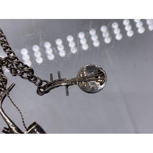 236 - A SILVER CHARM BRACELET WITH FISH,BANJO,OIL CONTAINER AND BIRD CAGE