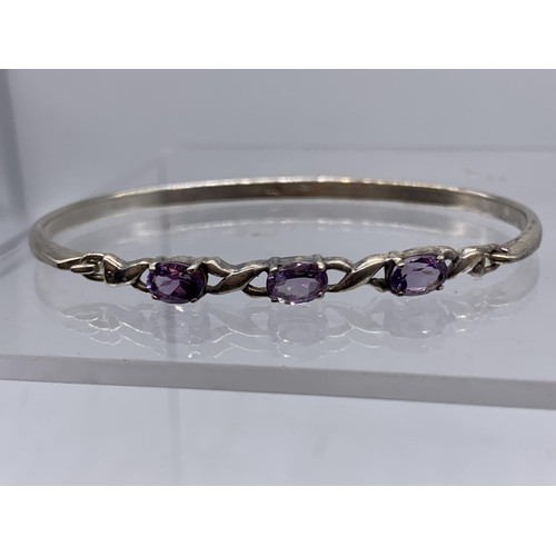 242 - A SILVER AND AMETYST SET BANGLE