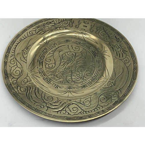 602 - A CHINESE BRASS PLATE DEPICTING  DRAGONS WITH MARKINGS TO BASE 11in Dia