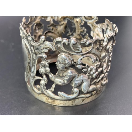 204 - AN ORNATE SILVER CUP HOLDER EMBOSSED WITH CHERUBS 16.9grms