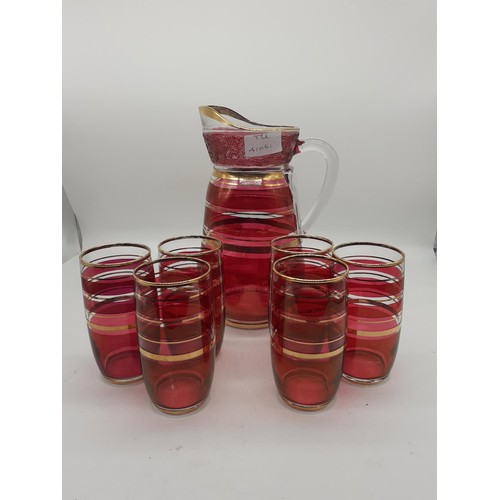 458 - A 1960s CRANBERRY AND GILT LEMONADE JUG AND 6 GLASSES