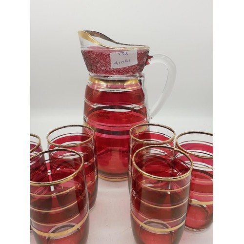 458 - A 1960s CRANBERRY AND GILT LEMONADE JUG AND 6 GLASSES