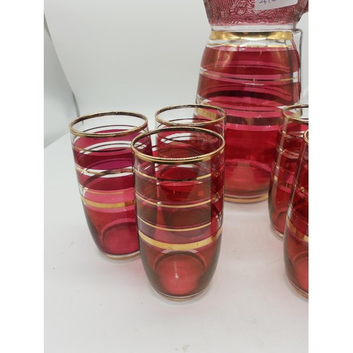 458 - A 1960s CRANBERRY AND GILT LEMONADE JUG AND 6 GLASSES