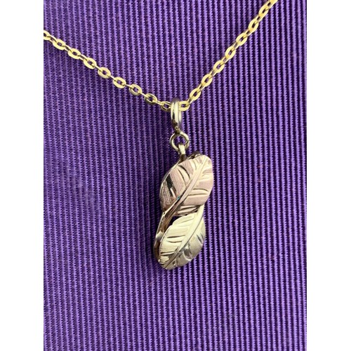 600 - A 9ct GOLD DOUBLE LEAF PENDANT ON A ROLLED GOLD CHAIN