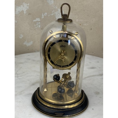 388 - A BRASS GERMAN WORKS ANNIVERSARY CLOCK UNDER GLASS DOME