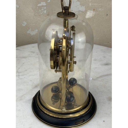 388 - A BRASS GERMAN WORKS ANNIVERSARY CLOCK UNDER GLASS DOME