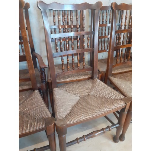 423 - A SET OF 8 OAK SPINDLE BACK CHAIRS WITH TURNED STRETCHES AND RUSH SEATS (2 CARVERS AND 6 CHAIRS)