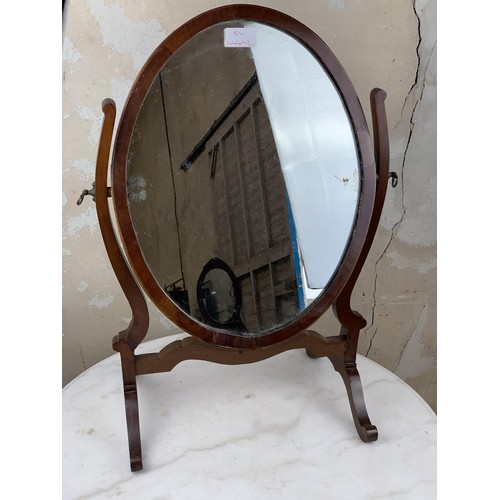 517 - AN OVAL INLAID DRESSING TABLE MIRROR IN A SHAPED FRAME