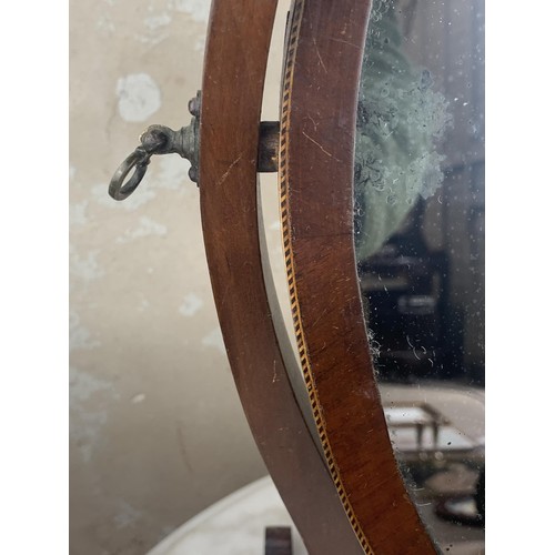 517 - AN OVAL INLAID DRESSING TABLE MIRROR IN A SHAPED FRAME