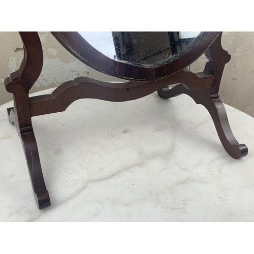 517 - AN OVAL INLAID DRESSING TABLE MIRROR IN A SHAPED FRAME